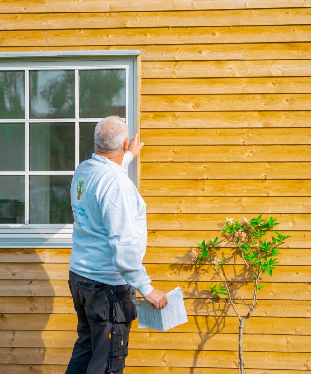 Tømrer undersøger hus af gult træ i skolskin