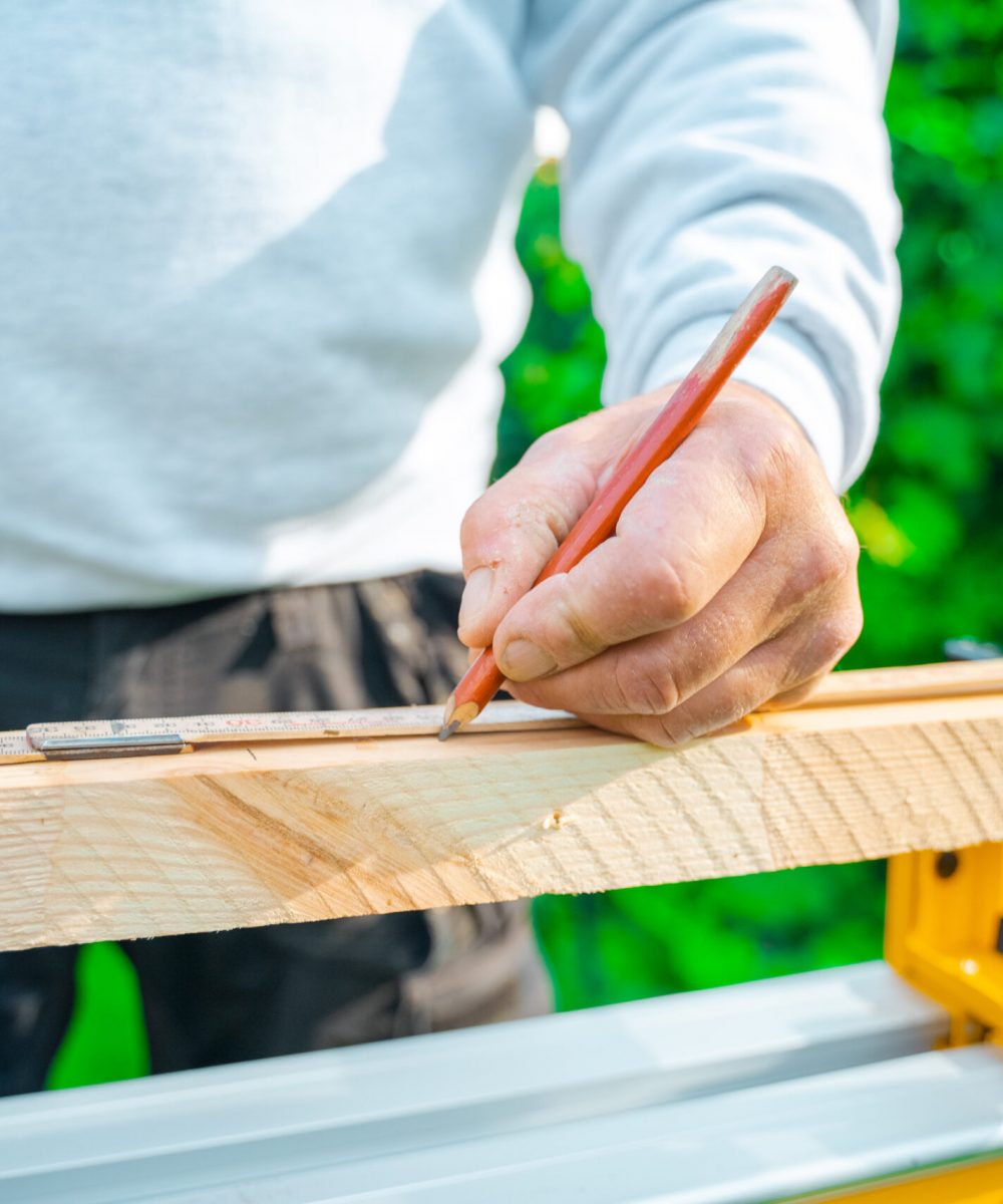 Tømrer bruger blyant på at tegne træ op. Tømrer bruger lineal